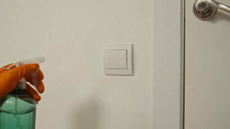 Cleaning Light Switch with Spray for Hygiene Purposes