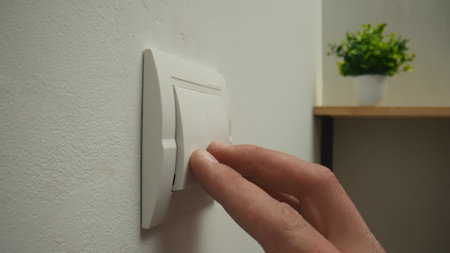 Person Switching Off Electric Light Using Wall Switch