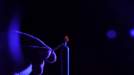 Ignition of a Candle with a Match Under Blue Lightingの写真素材