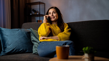 Young woman in the evening after work relaxing at home, sitting on the sofa in living room watching...
