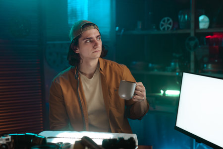 Person in a Cap Holding a Mug in a Dimly Lit Room