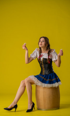Woman in Traditional Costume Sitting on Wooden Barrelの写真素材