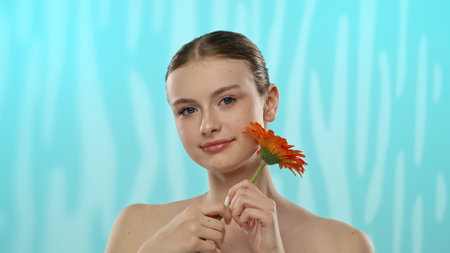 Young Woman Holding Gerbera Flower with Gentle Smileの写真素材