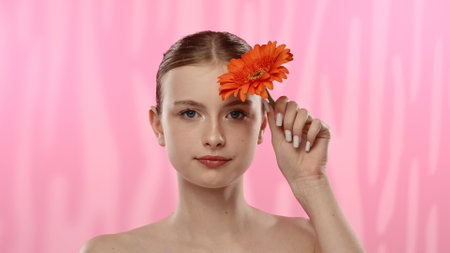 Young Woman with Bright Orange Flower on Vibrant Backgroundの写真素材