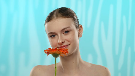 Young Woman Holding Gerbera Flower with Gentle Smileの写真素材