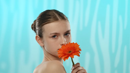 Young Woman Holding Bright Orange Flower with Soft Expressionの写真素材