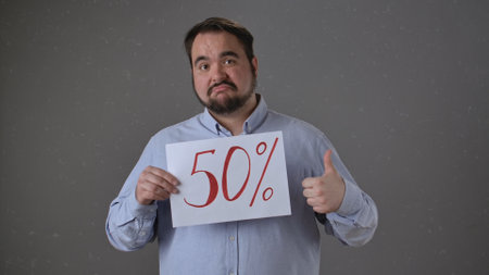 Man Holding a 50 percent Sign with Thumbs Up Gestureの写真素材