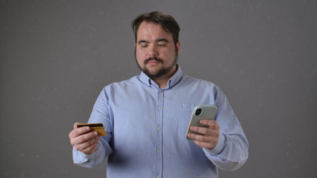 Man with smartphone and a credit card in studio ambianceの写真素材