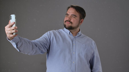 Man in Blue Shirt Taking a Confident Selfie with Smartphone