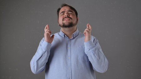 Man with Fingers Crossed Hoping for Good Luck in Studio Portraitの写真素材