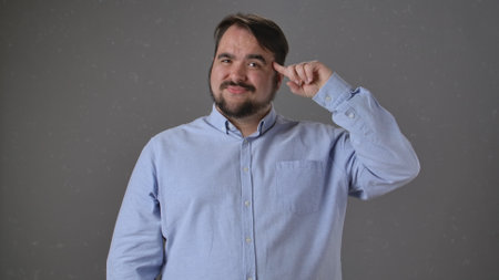 Man Pointing to Head with Confident Expression Indoorsの写真素材