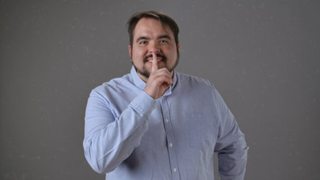 Person in Blue Shirt Making Silence Gesture with Index Finger