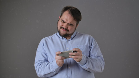 Man Frustrated With Mobile Game Holding Phone Intenselyの写真素材