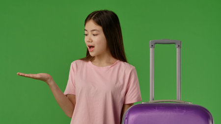 Girl with Luggage Surprised by Something in Her Handの写真素材