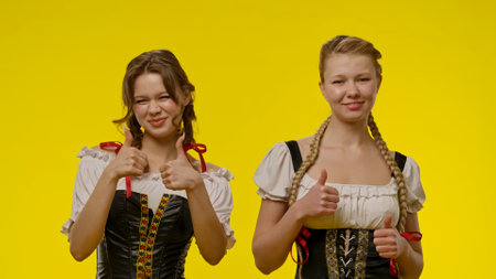 Smiling Women in Traditional Bavarian Dress on Yellow Backgroundの写真素材