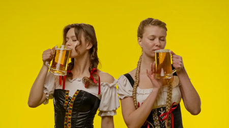 Two Women in Traditional Costumes Enjoying Beer Togetherの写真素材