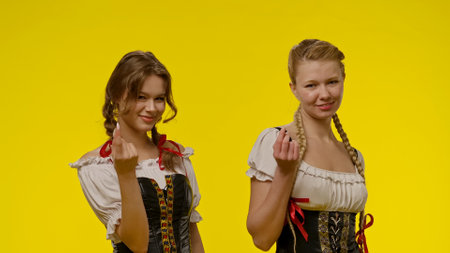 Two women smiling in traditional costumes against yellow backgroundの写真素材