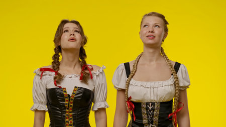 Two women smiling in traditional costumes against yellow backgroundの写真素材