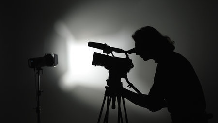 Silhouette of Videographer Filming in Studio with Professional Cameraの写真素材