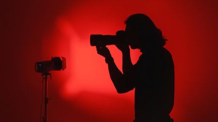 Silhouette of Photographer Capturing an Image Against Red Backgroundの写真素材