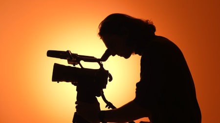 Silhouette of a Videographer with a Camera Against Sunset