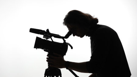 Silhouette of a Cameraperson Filming with a Professional Video Cameraの写真素材