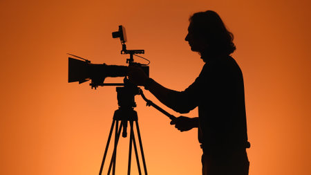 Silhouette of a Cameraman Adjusting Professional Video Equipment