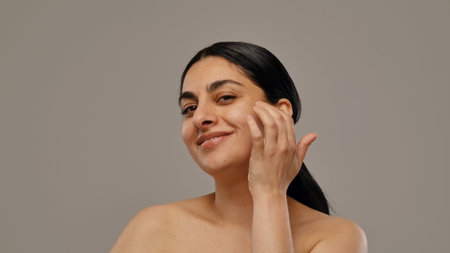 Smiling Woman with Healthy Skin Touching Her Faceの写真素材