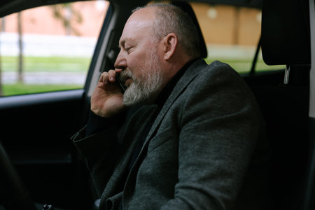 Elderly man behind the wheel of a car talking on a smartphone