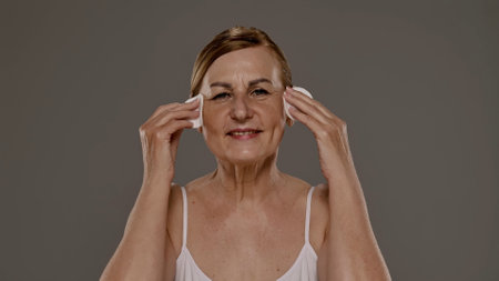 Senior Woman Cleansing Face with Cotton Pads at Home
