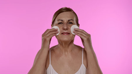 Senior Woman Cleansing Face with Cotton Pads at Home