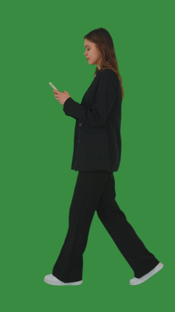 Businesswoman in Black Suit Using Mobile Phone While Walkingの写真素材