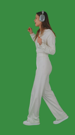 Person Enjoying Music with Headphones on Green Screenの写真素材
