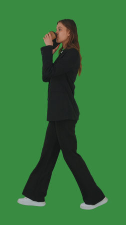 Young Woman Walking with Coffee on Green Screenの写真素材