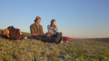 Young Participants Use a Laptop on a Picturesque Fieldの写真素材