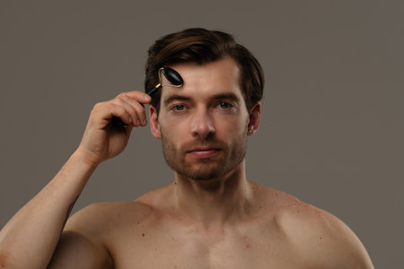 Man Using Black Jade Roller for Facial Skincare Routineの写真素材