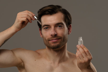 Man Applying Skincare Serum with Dropper for Smooth Complexionの写真素材
