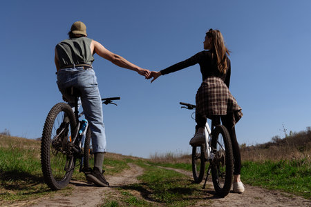 Couple Holding Hands While Cycling on a Sunny Dayの写真素材