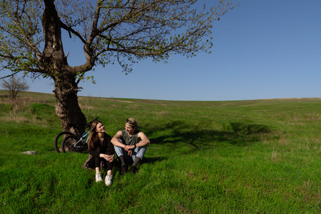 Couple Enjoying Relaxing Afternoon Under Tree in Green Meadowの写真素材