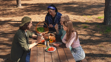 Group of Friends Enjoying a Picnic in a Sunny Forestの写真素材