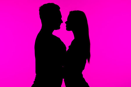 Silhouetted Couple Embracing Against Vibrant Pink Background