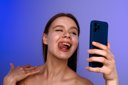 Woman Taking Playful Selfie with Blue Smartphoneの写真素材