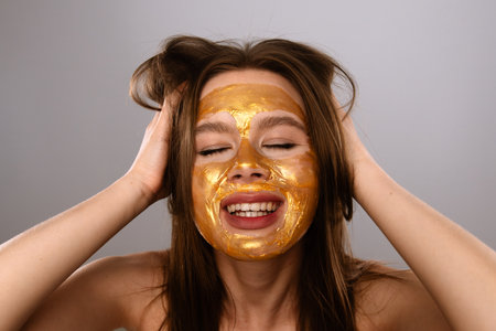 Joyful Woman Relaxing with Golden Facial Beauty Maskの写真素材