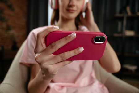 Young Woman Watching Video With Bright Pink Headphones While Relaxing