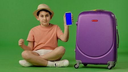 Young Traveler with Smartphone and Big Suitcase on Green Backgroundの写真素材