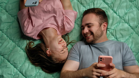 Happy Couple Relaxing on Bed with Smartphones