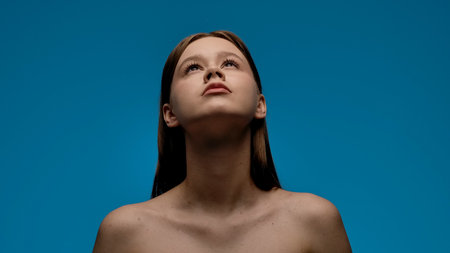 Portrait of Woman Looking Up Against Blue Backgroundの写真素材