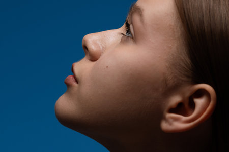 Profile View of Woman with Blue Background and Serene Expressionの写真素材