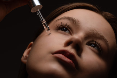 Young Woman Applying Facial Serum with Dropper for Skincare Routineの写真素材