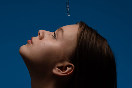 Close-up Portrait Depicting Facial Profile Against a Blue Backgroundの写真素材